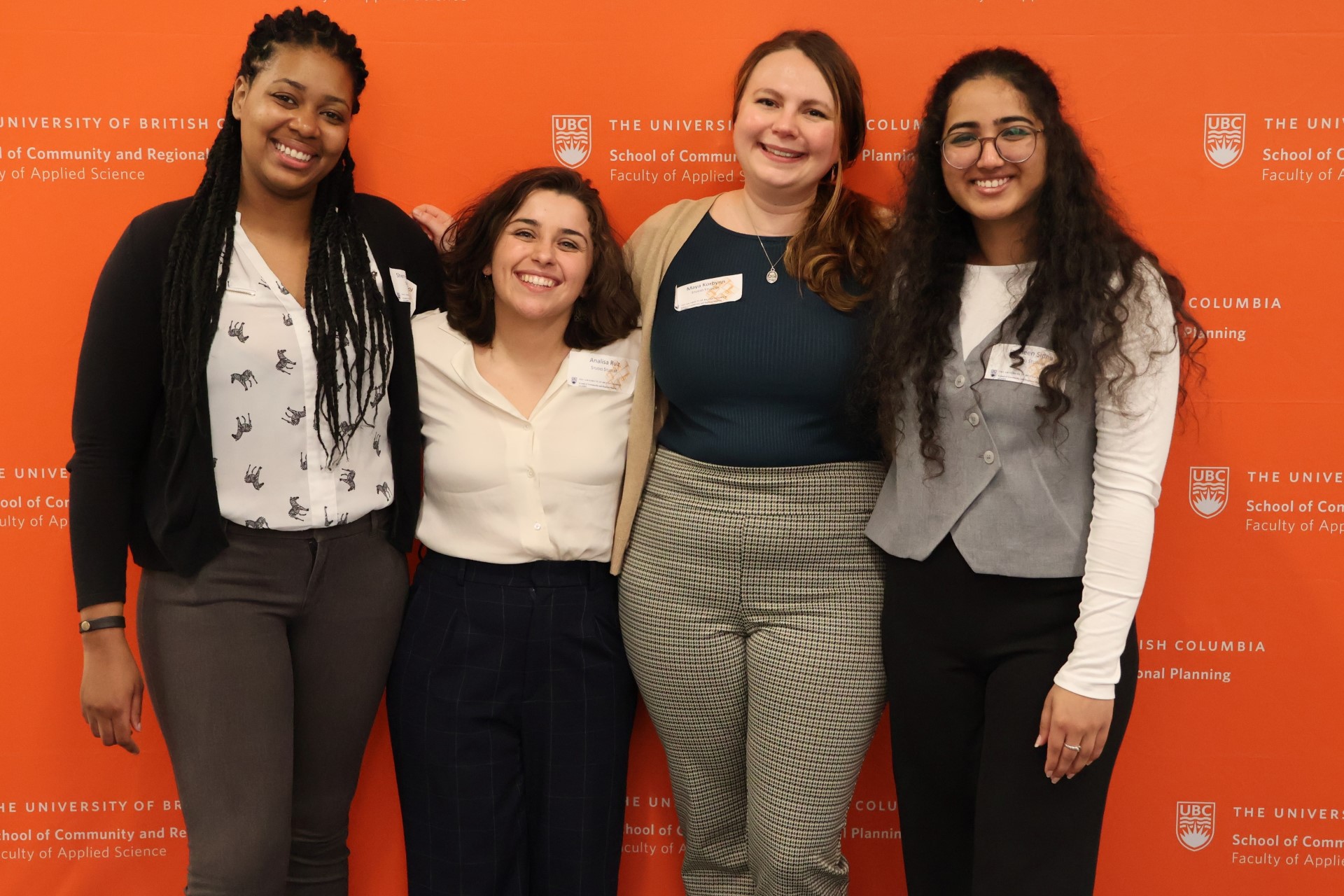 Four students arm-in-arm in front of giant SCARP logo