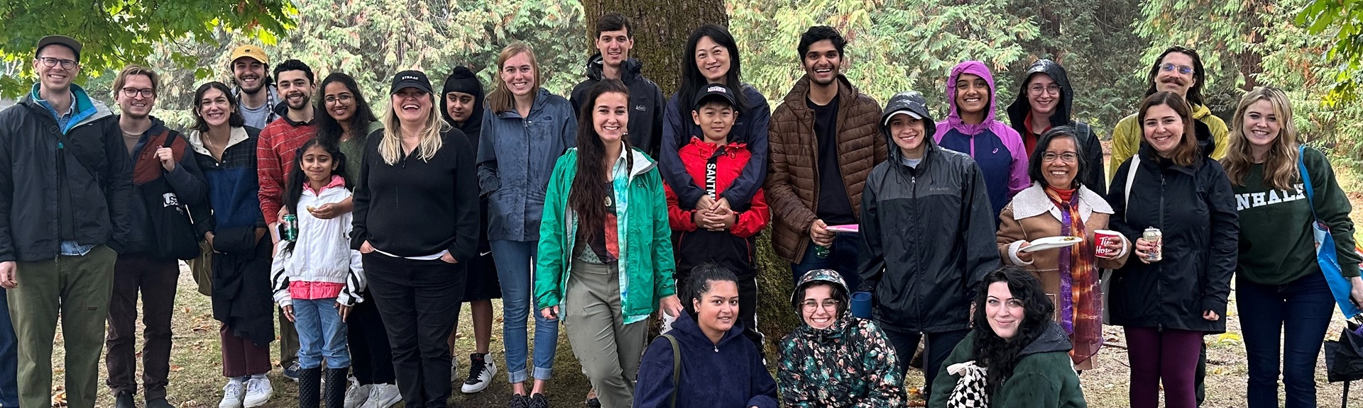 Group of students faculty and staff posing in wooded area