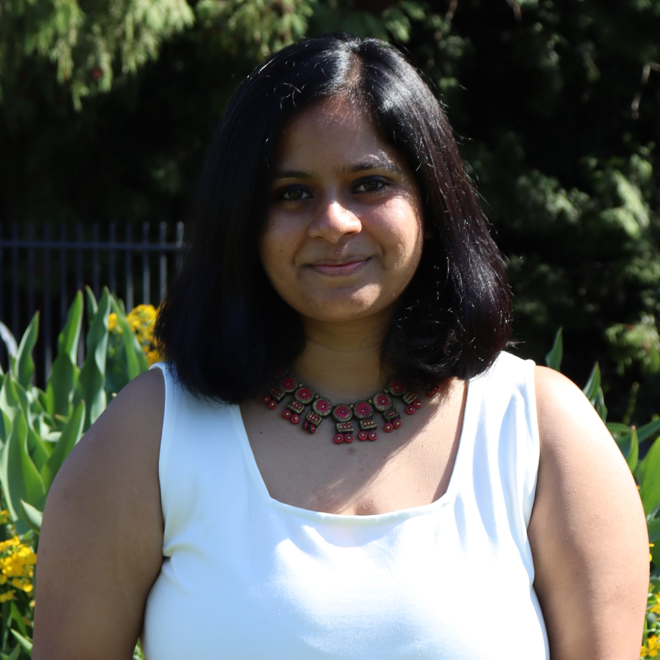Meghna Mahondas smiling in front of flowers