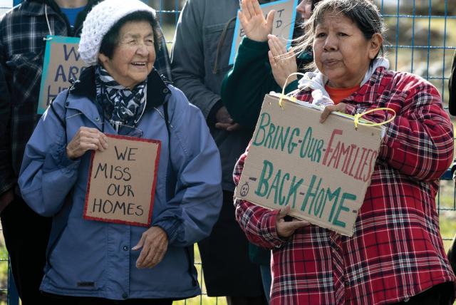 Two evacuees advocate for going back home with signs.
