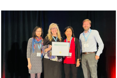 Emilie Adin and three others holding up an award document