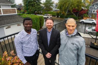 Three researchers pose on a wood patio in a neighbourhood