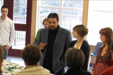 Man in blazer describing model neighbourhood to students