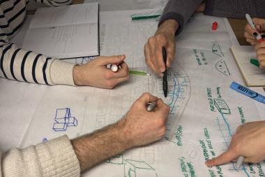 Multiple hands drawing a design sketch