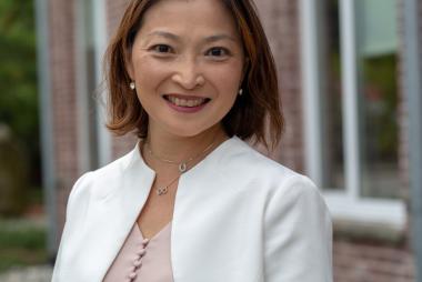 Woman in white blazer, outside brick building