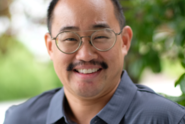 A smiling man in a polo shirt, outside among trees
