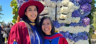Two women, one in PhD graduation regalia, one in professor regalia