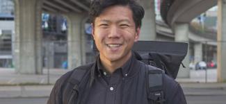 Man holding camera under Vancouver skytrain line