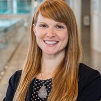 Maggie, in polkadot shirt, black cardigan, and teardrop necklace