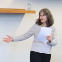 Heather, speech in hand, gesturing to her right